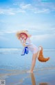 A woman in a straw hat is standing on the beach.