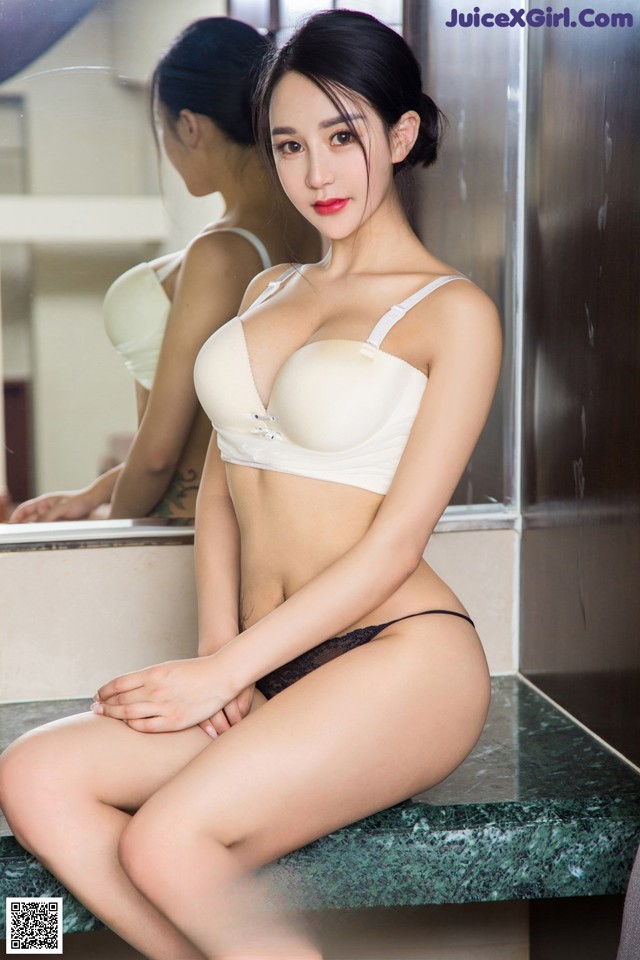 A woman sitting on a counter in front of a mirror.
