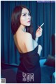 A woman in a black dress smoking a cigarette.