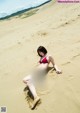 A woman in a red bikini laying on a sandy beach.