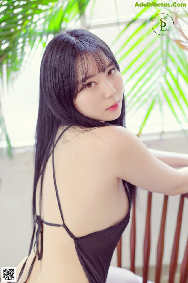 A woman in a black bathing suit sitting on a chair.
