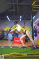 A woman in a yellow shirt and black shorts doing a squat with a resistance band.