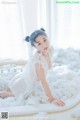 A woman in a white dress sitting in a bathtub filled with foam.