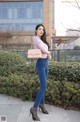 A woman in a pink shirt and blue jeans posing for a picture.