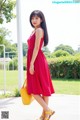 A woman in a red dress is holding a yellow bag.