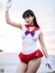 A woman in a white shirt and red skirt posing on a beach.