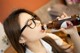 A woman wearing glasses drinking from a beer bottle.