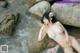 A woman in a bikini laying on a rock in the water.