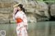 A woman in a pink kimono standing by a body of water.