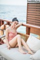 A woman in a pink bathing suit sitting on a lounge chair.