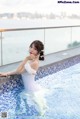 A woman in a white corset sitting in a swimming pool.