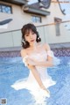 A woman in a white dress sitting in a pool.