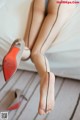 A close up of a woman's legs and shoes on a bed.