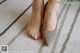 A woman's feet with red nail polish on a carpeted floor.