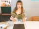 A woman sitting at a table reading a book.