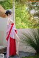 A woman in a red and pink kimono posing for the camera.