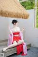 A woman in a red dress sitting on a wooden bench.