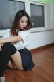 A woman sitting on the floor in a school uniform.