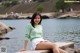 A woman sitting on a rock by the water.