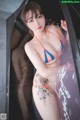 A woman in a bikini standing in a bathtub.