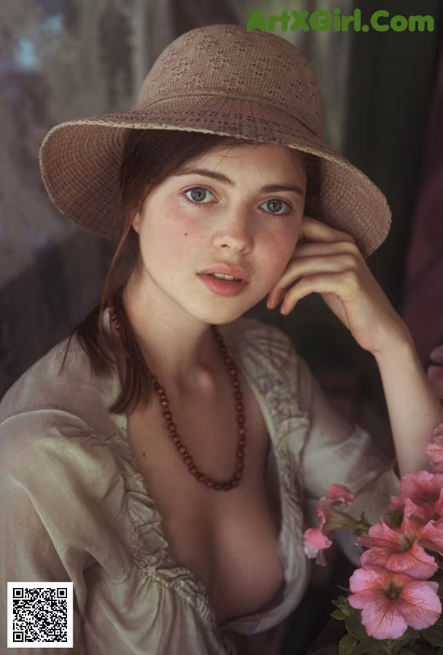 A woman in a straw hat sitting next to a bunch of flowers.