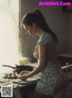 A woman in a blue and white dress preparing food in a kitchen.