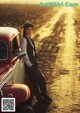 A woman leaning on the hood of a red car.