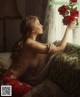 A naked woman sitting on a couch holding a bunch of red roses.