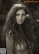 A woman with long curly hair and a flower in her hair.