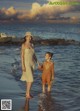 A woman and a little girl walking on the beach.