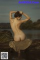 A naked woman sitting on a log in the water.