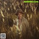 A young boy wearing a straw hat sitting in a field of tall grass.