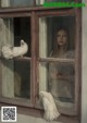 A woman looking out of a window with two white doves.