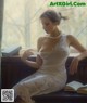 A woman in a white dress sitting on a window sill.