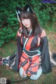 A woman in a black and red kimono sitting on the ground.