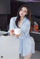 a woman in a blue shirt holding a cup of coffee