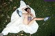 A woman laying on a white fur rug in the grass.