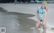 A woman in a blue bikini standing in the water.