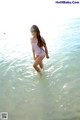 A woman in a pink bathing suit standing in the water.