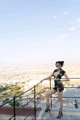 A woman in a black dress standing on a balcony.