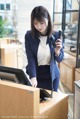 A woman in a business suit talking on a phone at a desk.