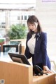 A woman in a business suit standing at a reception desk.