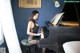 A woman sitting at a piano in a room.