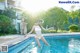 A woman in a white bathing suit and hat jumping into a swimming pool.