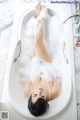 A woman laying in a bathtub covered in foam.