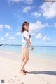 A woman standing on a sandy beach next to the ocean.