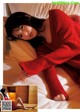 A woman in a red sweater laying on a bed.