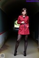 A woman in a red coat is standing in a tunnel.