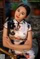 A woman in a cheongsam sitting on a chair.