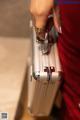 A woman in a red dress holding a silver suitcase.